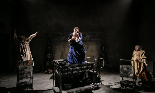 three women in ragged dresses dance and sing 