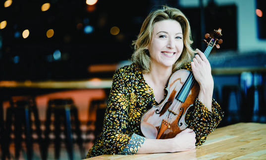 Candida Thompson sitting at table holding violin