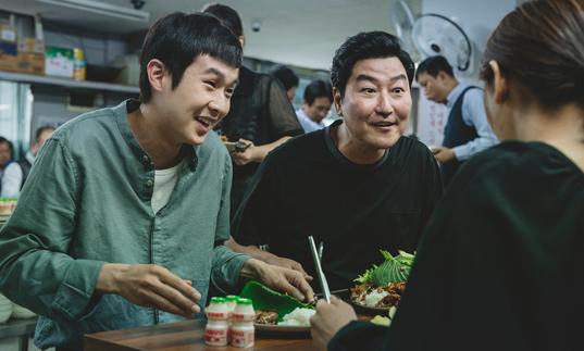 father and son smiling up at someone across the dinner table