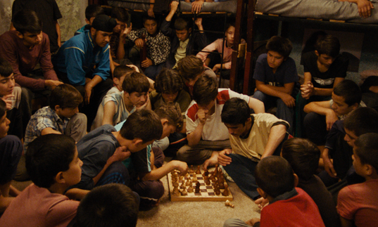 A large group of young boys play chess in The Orphanage