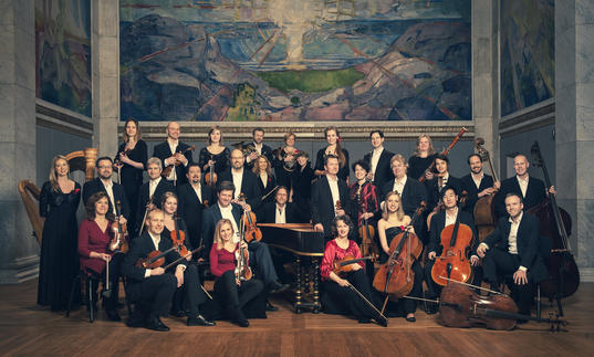 A portrait of the Norwegian Chamber Orchestra clutching their instruments