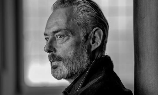 A black and white portrait of Mark Padmore gazing into the distance