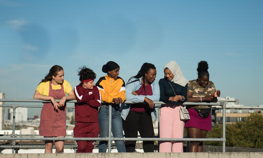 A group of girls stand in a line talking and laughing