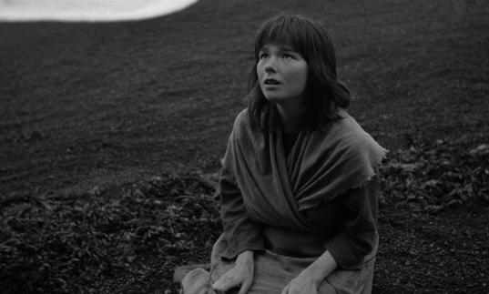 A black and white image of young Bjork kneeling on the ground looking up