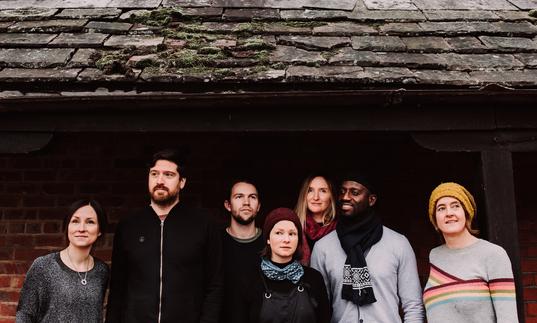 The performers from The Lost Words stand outside a house with a slated roof