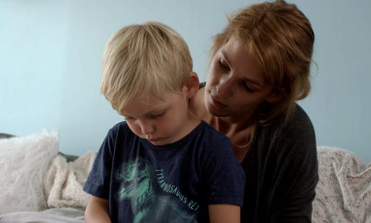 a little boy sits on a woman's lap looking downwards