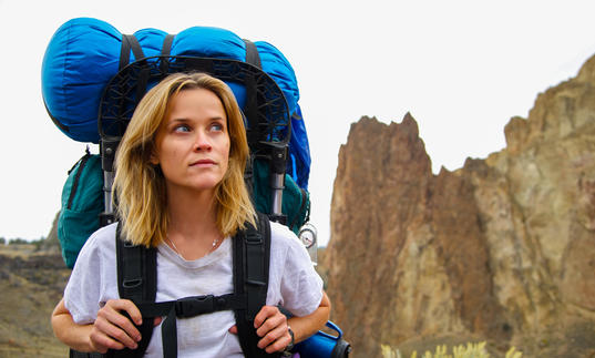 reese witherspoon with hiking bags in the middle of some mountains