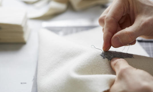 Person embroidering a white cloth 