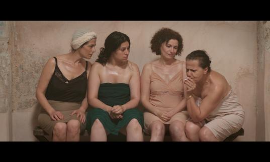 a group of women are in a bathing house together, talking