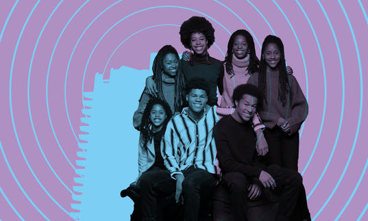 The Kanneh-Mason Family smiling with the Barbican tower illuminated on them