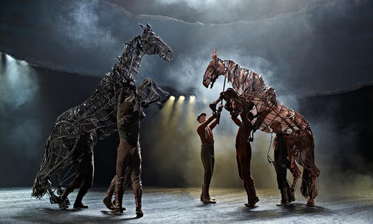 puppet horses rearing on their hind legs whilst men are trying to control them
