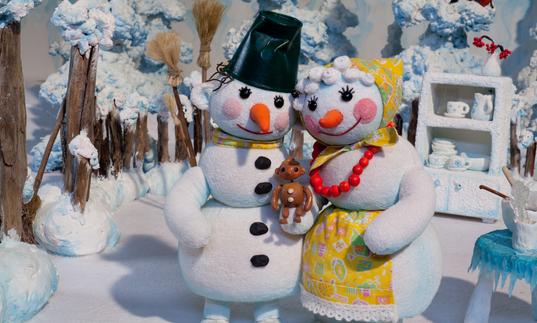 A snow man and snow woman hold a snow baby