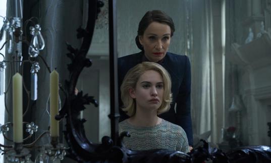 Lily James (playing Rebecca) looking into a mirror with Kristen Scott Thomas standing over her