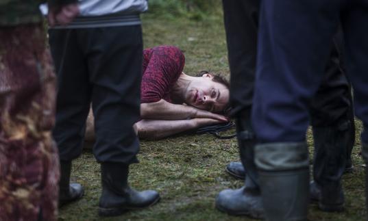 man lying on the ground with people standing around him