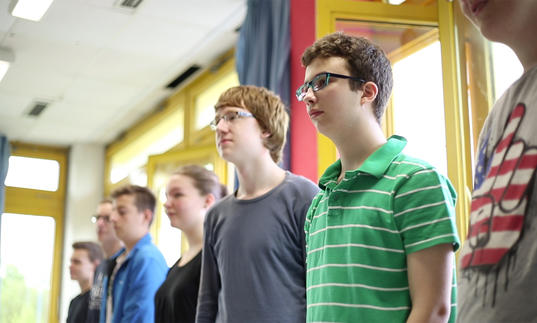 a group of teenagers stand in a line next to each other