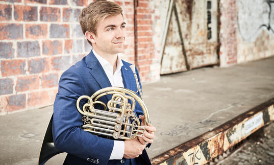 Ben Goldscheider looking into the distance with his French Horn