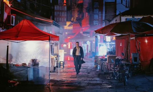 a man walks through the darkly lit streets of a city