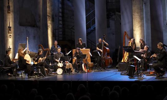 L'Arpeggiata on a lit stage, playing their period instruments