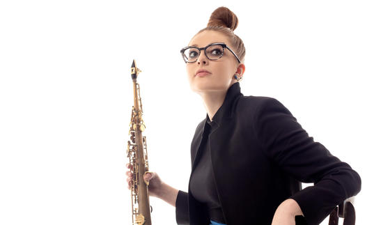 Jess Gillam sitting on a chair holding her saxophone