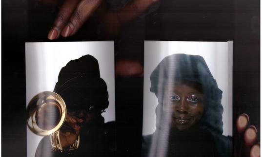 a very close up shot of Klein holding up two passport sized photos of herself