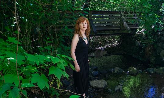 Sarah Cahill standing in a garden in front of a bridge