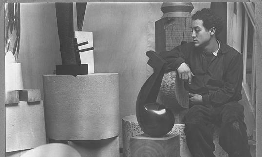 A young Isamu Noguchi in his studio surrounded by sculpture