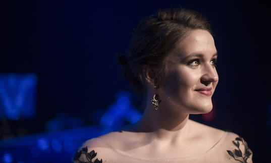 Lise Davidsen looking to her left, smiling, in front of a blue-lit backdrop