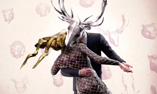 Two dancers embrace while wearing animal-themed masks.