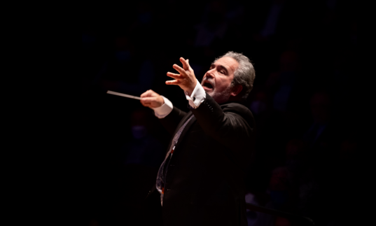 A spotlight shines on Carlo Rizzi as he conducts