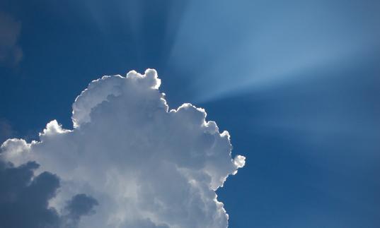 Photo of the sun's rays shining from behind a cloud