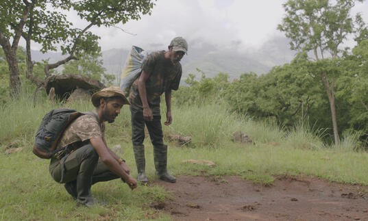 A still from The Road to Kuthriyar, two men in a forest