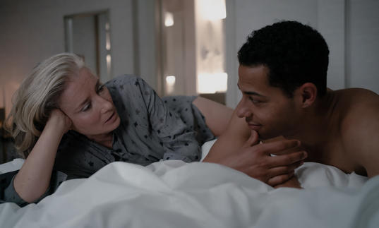 Emma Thompson and Daryl McCormack lie on a bed and look at each other