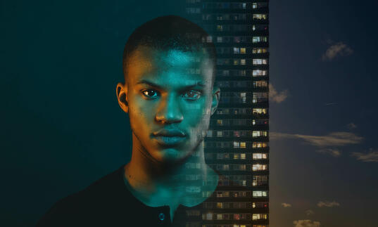 Black male portrait next to tower block