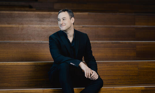 Jonathan Cohen sitting on wooden steps