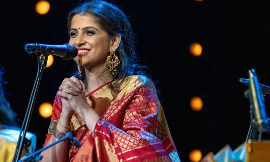 Kaushiki Chakraborty performing on stage smiling in a sari