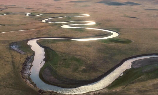 Still image from River, showing a drone shot of a large meandering river