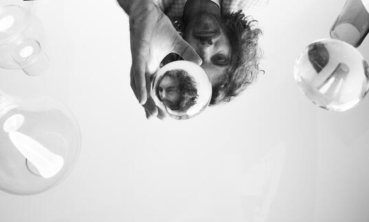 Black and white conceptual image of Blanco White peering through a glass ball