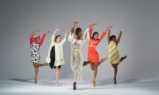 Five ballet dancers pose in costumes