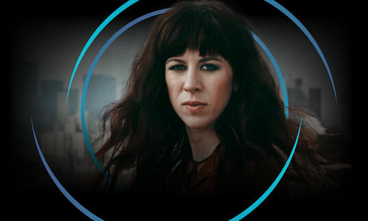 Missy Mazzoli looking at the camera, with circular blue swirls around her head