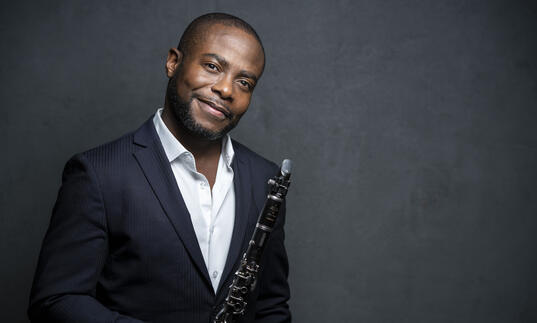 Anthony McGill smiling at the camera while holding his clarinet