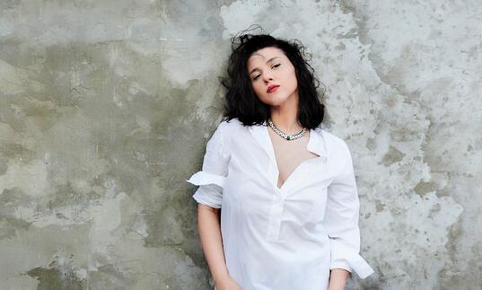 Khatia Buniatishvili standing against a stone wall