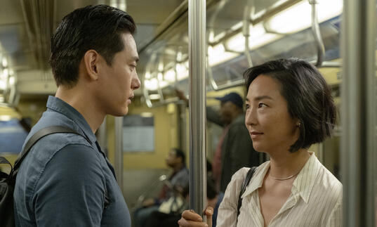 A man and a woman look at each other on the subway
