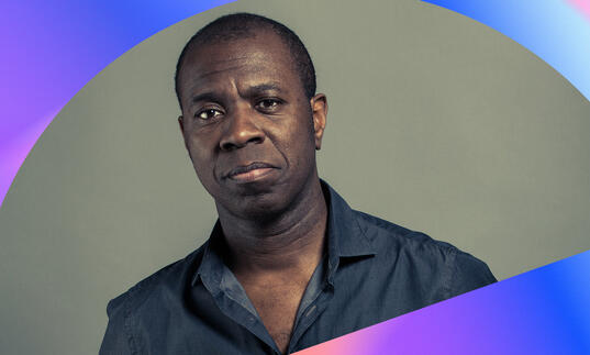 Clive Myrie with blue and purple blocks of colour framing the photo