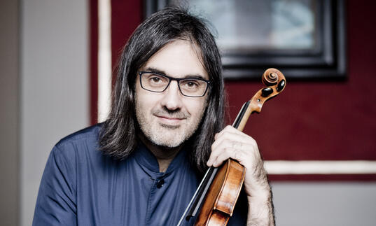 Leonidas Kavakos looking at the camera while holding his violin
