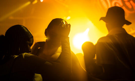 People dancing in a nightclub bathed in orange light