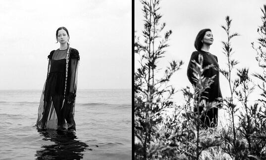 Lucinda Chua & Gayla Bisengalieva stand in landscape and black and white 