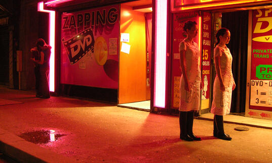 Two people look on in a neon soaked street