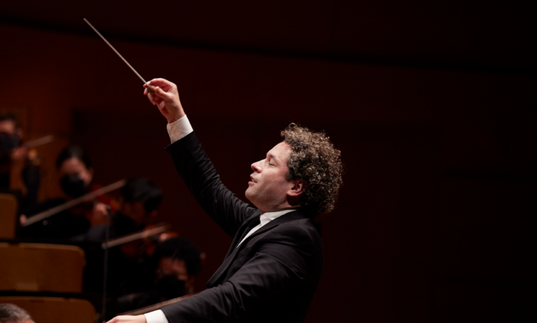 A side-on shot of Gustavo Dudamel conducting