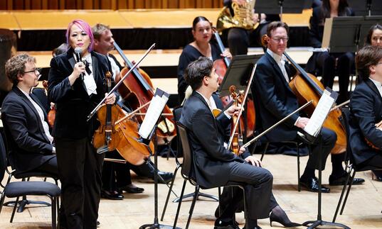 LSO Violinist Maxine Kwok introducing the LSO on the Barbican stage, at a Half Six Fix concert.