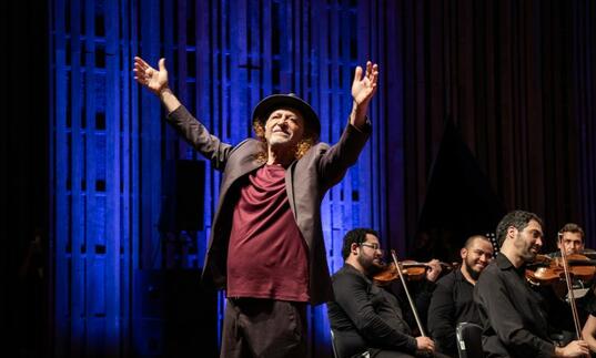 Alceu Valenca on stage with his arms in the air 